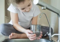 Girl running water into glass